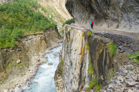 Trekker with backpack walking on trail with beautiful rocks and mountain river. Travel concept. Focus on woman.の写真素材