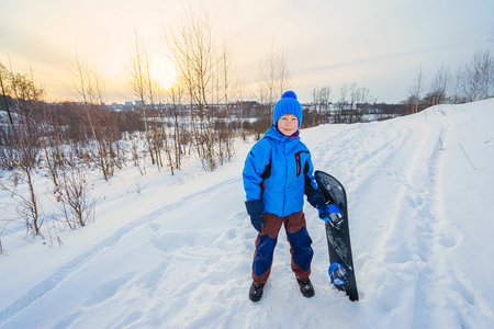 Small boy with snowboard on the nature.の写真素材