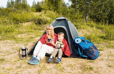 Happy  mother and son camping in tent and drinking tea on the nature. の写真素材