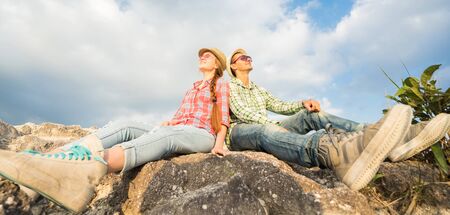 Happy smiling couple sitting on the mountain top. Selective focus. Banner.の写真素材