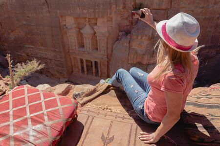 Tourist taking photo of Petra from top of rock. The treasury or Al Khazna, it is the most magnificant and famous facade in Petra, Jordan. Selective focus.の写真素材