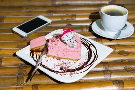 Close up of vegan cake, cup of coffee and mobile phone lying on a bamboo table. Selective focus. の写真素材
