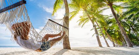 Woman relaxing on hammock on the beach. Travel and vacation concept. Banner edition.の写真素材