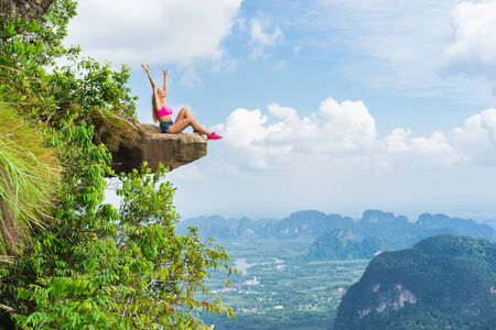 Woman sitting on the top of mountain with a breathtaking view of the landscape with valley and rocks. の写真素材