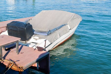 Motorboat covered in a rain tarp and wooden pier.の写真素材
