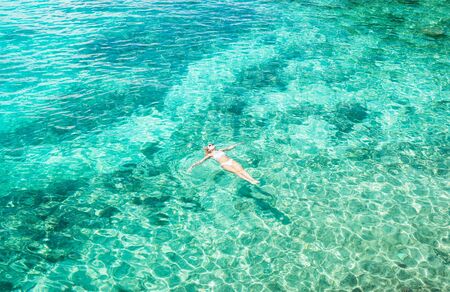 Young woman swimming in the beautiful blue sea. Overhead view. Aerial shot.の写真素材