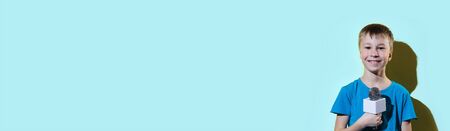 Little happy journalist with microphone isolated on color background. Banner edition.の写真素材