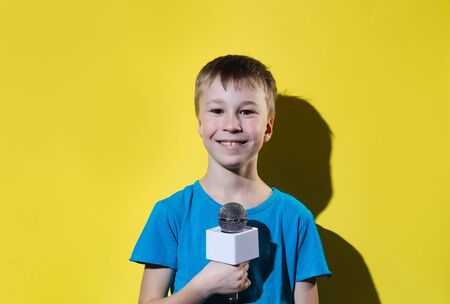 Little happy journalist with microphone isolated on yellow color background. の写真素材