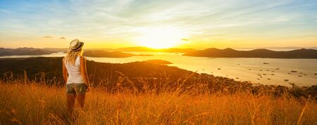 Woman enjoying sunset from mountain top. Islands and sky on background.  Banner and panoramic edition.の写真素材