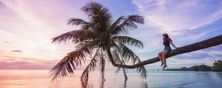 Woman in hat sitting on the beach palm and looking on beautiful sunset. Banner edition.の写真素材