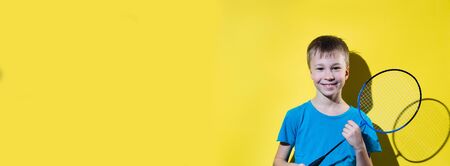 Happy child with badminton racket isolated on yellow background. Banner edition.の写真素材