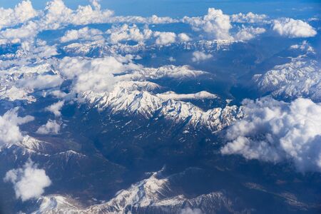 Aerial view of snowy Alps mountains with clouds.の写真素材