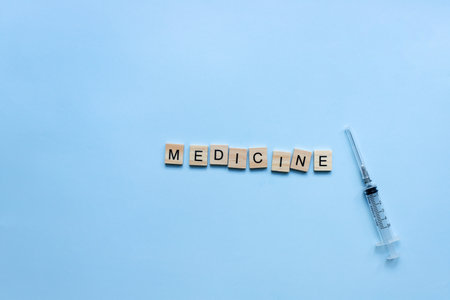 The word medicine from wooden letters on a blue background. Syringe, vaccine, injection, inoculationの写真素材