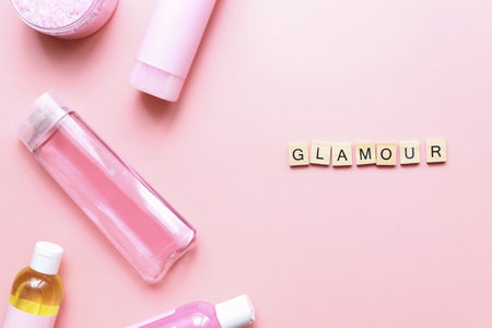 Flat lay word glamor from wooden letters on pink background. bottle mockup. spa jarsの写真素材