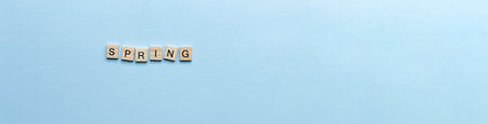 Banner The word spring laid out in wooden letters. Flat lay spring on blue backgroundの写真素材
