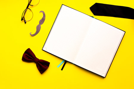 Flat lay mustache, glasses, bow tie and necktie on a yellow background. Mockup male diary. man's deskの写真素材