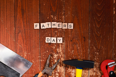 Flat lay happy father's day lined with letters. Building tools on a wooden background. Repair and constructionの写真素材