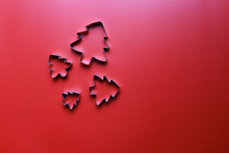 Flay lay molds for cookies in the shape of Christmas trees on a red backgroundの写真素材