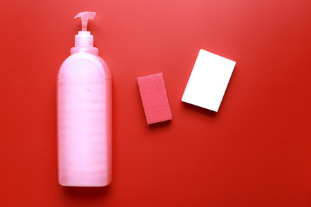 Flat lay dishwashing detergent and sponge on red background. cleaning.の写真素材