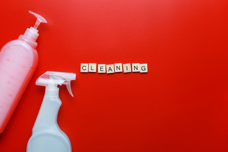 Flat lay cleaning products and sponges on a red background. Word cleaning from letters. Cleaning Spray Mockupの写真素材