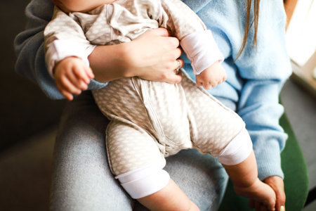 Mom is holding a baby in her arms. Baby in cotton overallsの写真素材