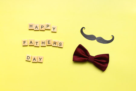 happy fathers day. Flat lay mustache. bow tie on a yellow background. fathers day lettering wordの写真素材