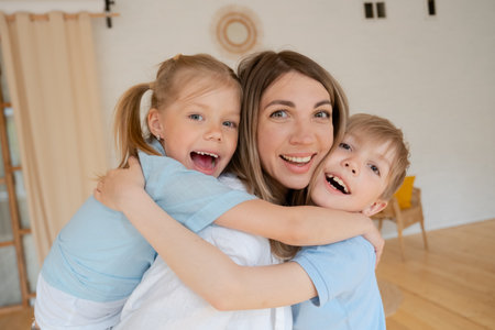 Two children son and daughter hug their mother. Happy loving family standingの写真素材