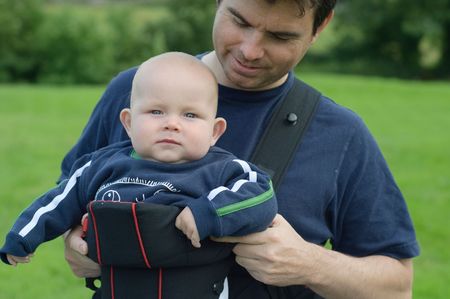 father helping son into baby carrier slingの写真素材
