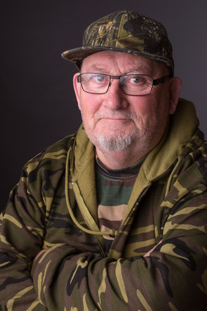Portrait of a senior elderly old man wearing camouflage clothing and glasses. senior citizen face is happy and smiling.の写真素材