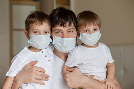 Father and sons in medical masks at home. Image with selective focus. high quality photoの写真素材