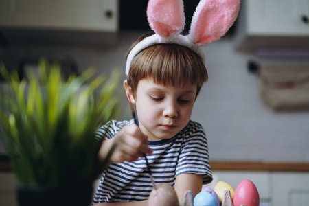 Cute little boy coloring eggs for easter. Image with selective focus