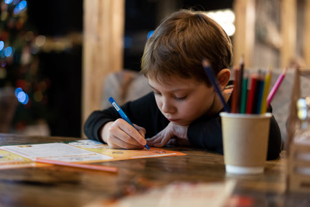 cute little boy drawing with color pencils sitting at the table in restaurant. Image with selective focusの写真素材
