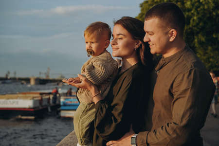 beautiful caucasian young family couple holding baby son at the quay of city Saint-Petersburg, Russia. high quality photoの写真素材