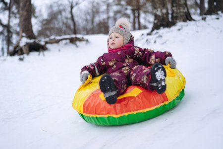 cute caucasian girl having a ride on snow tubing in winter park. Image with selective focusの写真素材