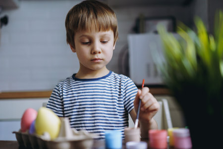 Cute little boy coloring eggs for easter. Image with selective focusの写真素材