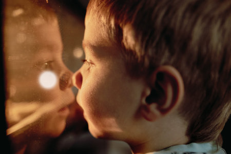 little boy looking through glass in oven where cookies baking. Christmas holiday concept. Image with...