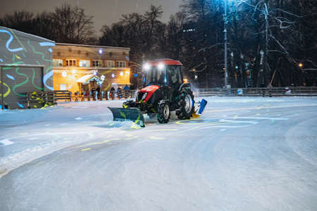 tractor cleaning ice from now on ice rink decorated and illuminated for christmas. Image with selective focus, motion blur and noise effectのeditorial素材