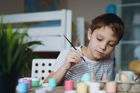 Cute little boy coloring eggs for easter. Image with selective focus