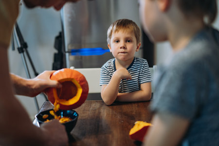 Caucasian man with his cute sons carving a pumpkin to make traditional Jack lantern.の写真素材