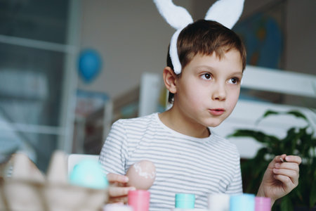 Cute little boy coloring eggs for easter. Image with selective focus