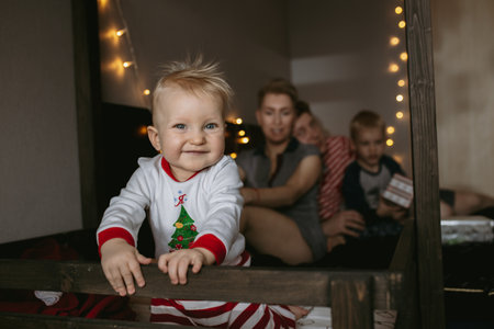 happy family waiting for christmas. Little girl on the foreground. Family with mom, dad and brother on background. Image with selective focus and noise effectの写真素材