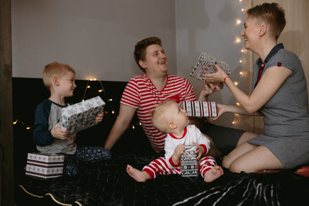 Happy family waiting for christmas. Family with mom, dad and brother giving each other presents. Image with selective focus and noise effectの写真素材