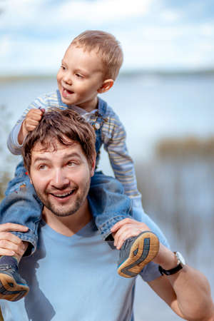 father and son. Boy sitting on man shoulders. Image with selective focusの写真素材