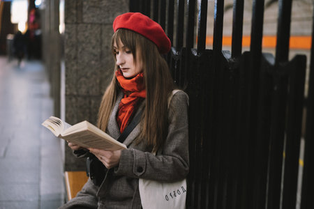 Beautiful Caucasian woman wearing coat, beret, scarf and bag with text (happiness) sitting alone on...