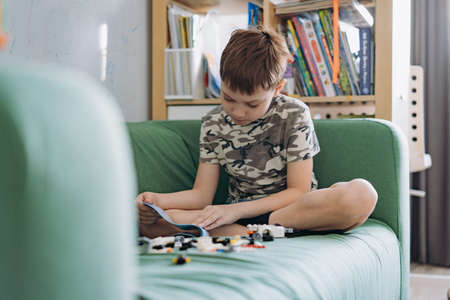 Little caucasian boy constructing a car with plastick blocks reading instructions book. Image with selective focusの写真素材