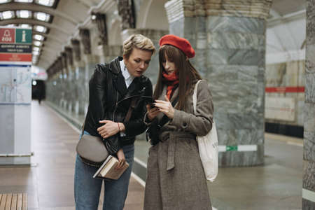 caucasian girls standing on platform of metro station reading something in platform. high quality photoの写真素材