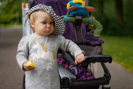 cute little girl learning to walk cute little girl learning to walk holding a baby carriage and...