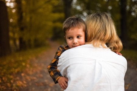 Young mother hugging her little son in autumn park. high quality photo