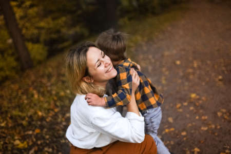 Young mother hugging her little son in autumn park. high quality photoの写真素材