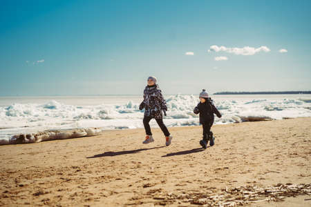 boys running along the beach of finland gulf covered with ice. Image with selective focus.の写真素材